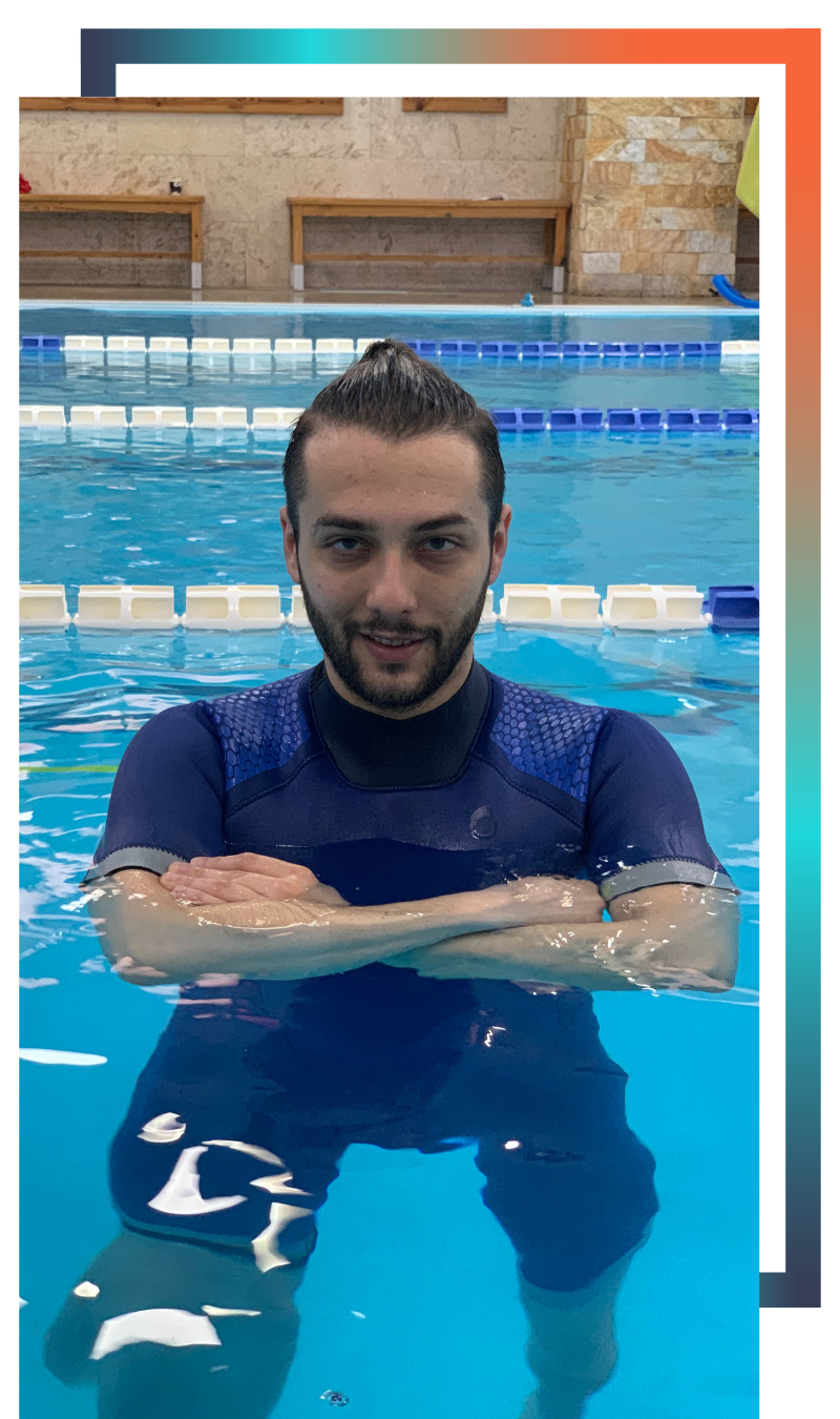 man in a blue wetsuit smiling to camera in a swimming pool